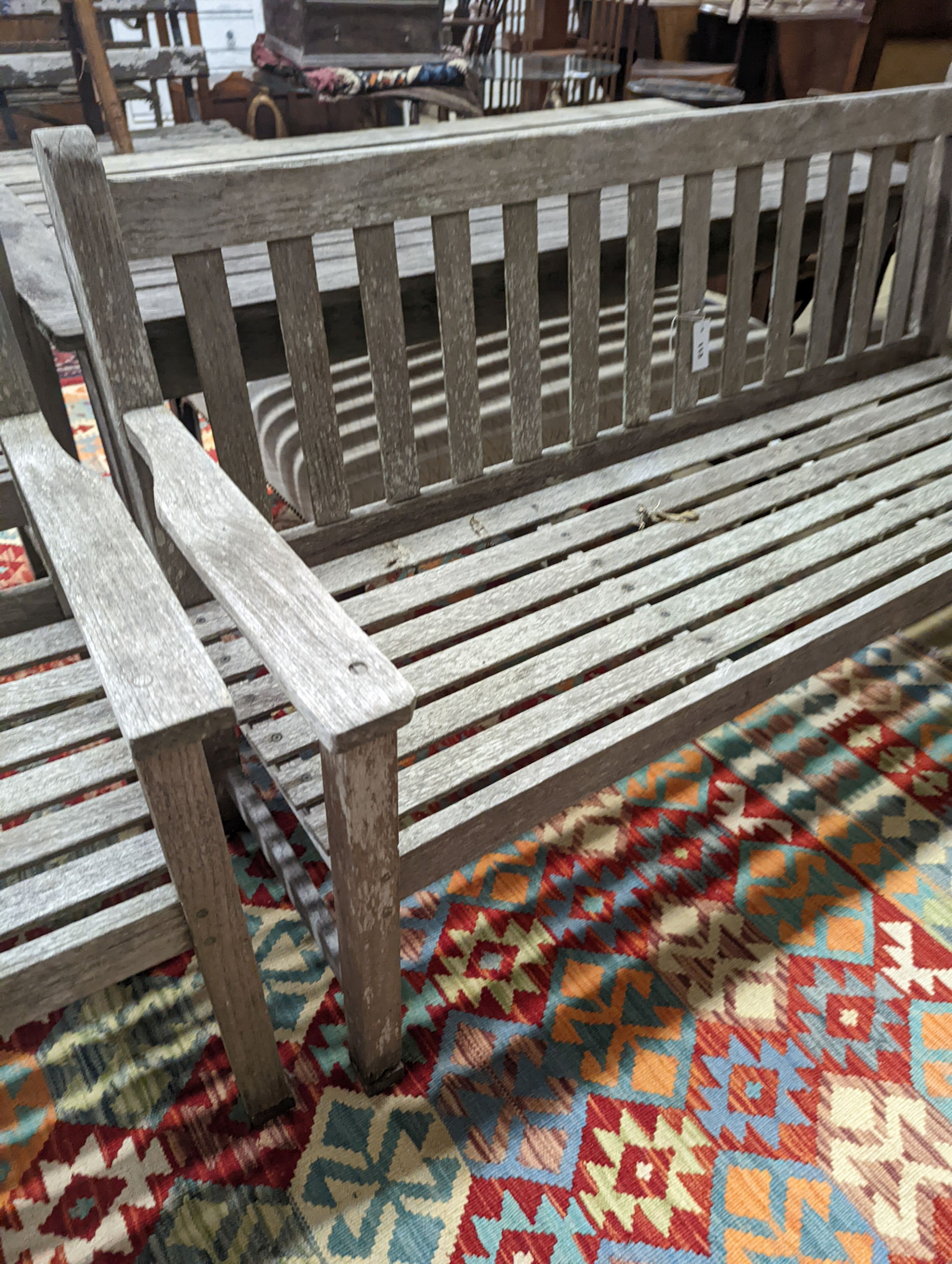 A Barlow type weathered teak garden suite, comprising rectangular table, length 149cm, depth 71cm, height 70cm, a bench and two armchairs